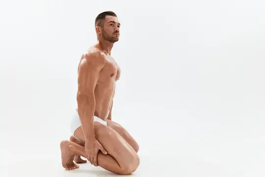 Спортивный мужчина, культурист в трусах, с обнаженным торсом и прессом в полный рост на фоне, фитнес-занятия