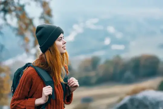 Женщина-туристка с рюкзаком гуляет осенью