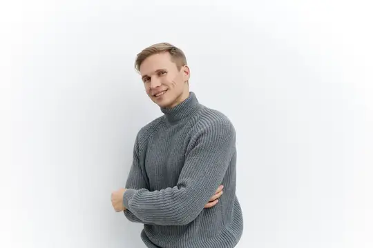 Улыбающийся светловолосый мужчина в сером свитере на белом фоне