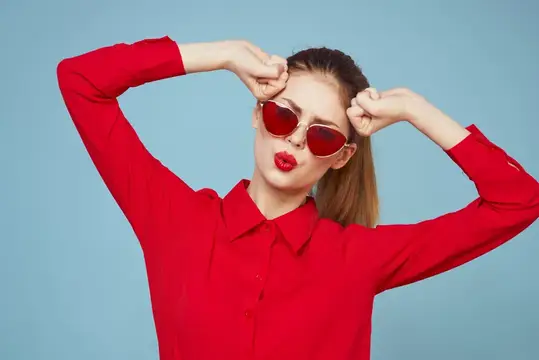 Красивая женщина в тёмных очках, красная рубашка, яркий макияж, эмоции, привлекательный взгляд, голубой фон