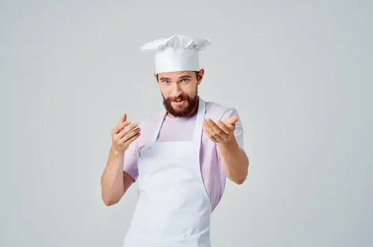 Эмоциональный шеф-повар жестикулирует руками, занимаясь профессиональным приготовлением изысканных блюд
