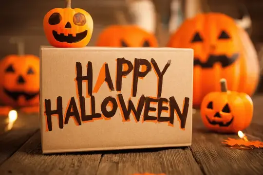 Светящиеся тыквы с улыбками и надпись Happy Halloween на деревянном столе