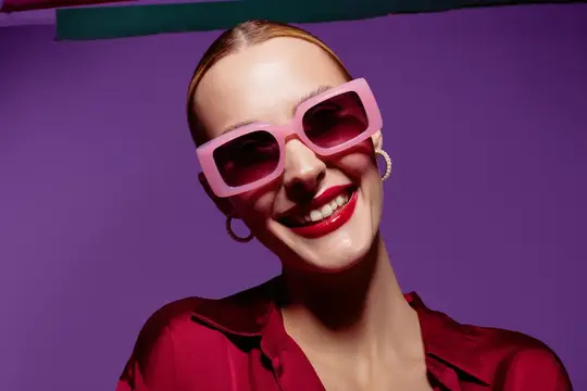 Улыбающаяся женщина в розовых очках на фиолетовом фоне