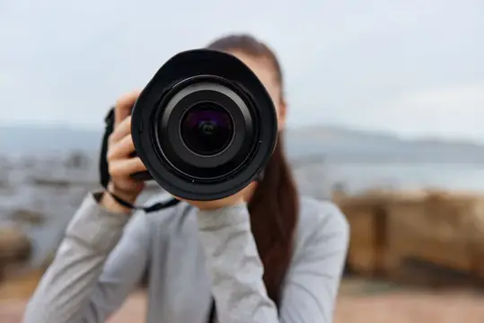 Девушка фотографирует через большой объектив на фоне моря