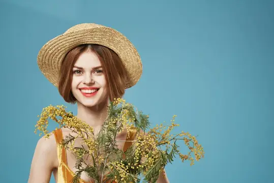 Улыбающаяся девушка в соломенной шляпе с ветками мимозы