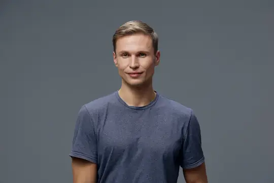 Молодой блондин в синей футболке на сером фоне
