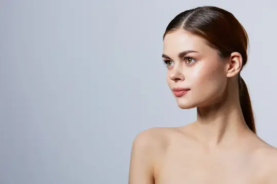 Молодая женщина с гладкой причёской и естественным макияжем смотрит в сторону