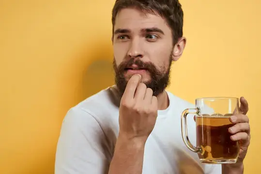 Задумчивый бородатый мужчина с кружкой чая на жёлтом фоне