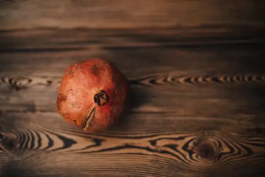 Спелый гранат лежит на тёмных деревянных досках