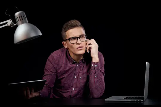 Менеджер-мужчина в помещении на тёмном фоне, общение, красная рубашка, модель в очках, новые технологии, бизнес, финансы