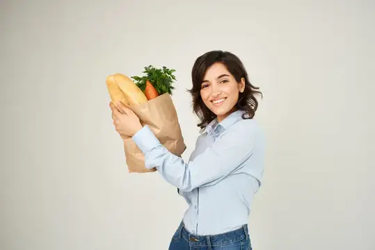Жизнерадостная женщина с пакетом продуктов в супермаркете, шопинг, образ жизни