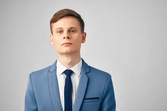 Молодой человек в синем костюме и галстуке на сером фоне