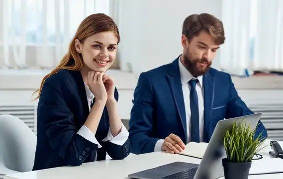 Улыбчивая женщина и бородатый мужчина в офиса за работой