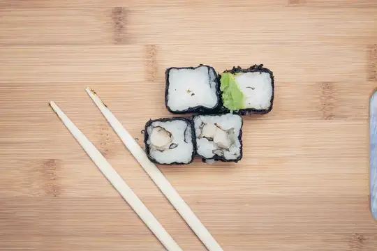 Роллы с начинкой и палочки на бамбуковой доске