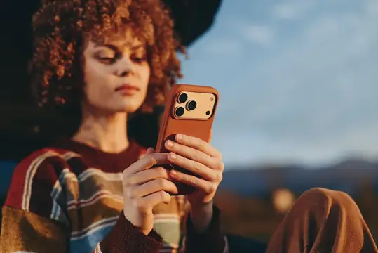 Рыжеволосая девушка со смартфоном в руках на закате
