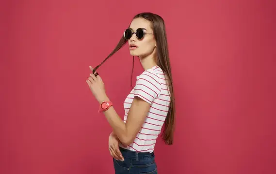 Симпатичная женщина в полосатой футболке, студийная одежда, розовый фон