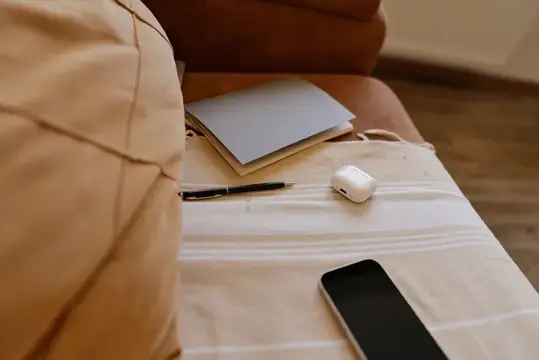 Блокнот, ручка и наушники на диване рядом со смартфоном