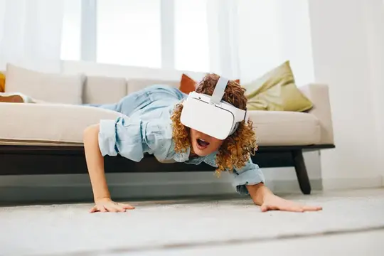 Кудрявая девочка в VR-очках ползёт по полу у дивана
