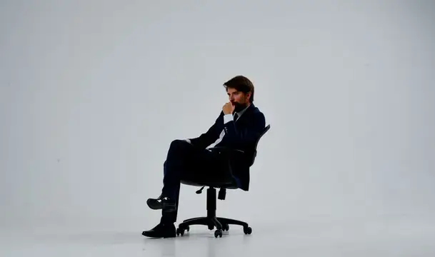 Задумчивый мужчина в костюме сидит на офисном стуле