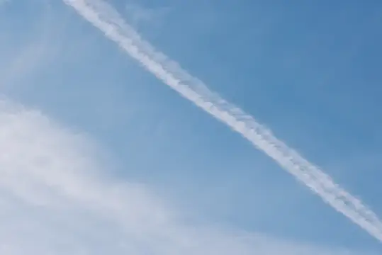 Белый след самолёта на фоне голубого неба