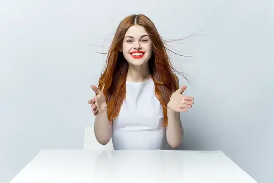 Весёлая симпатичная рыжеволосая женщина с красными губами улыбается