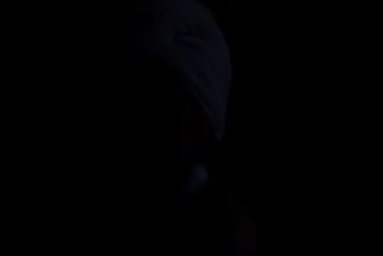 Тёмный силуэт человека в капюшоне на чёрном фоне