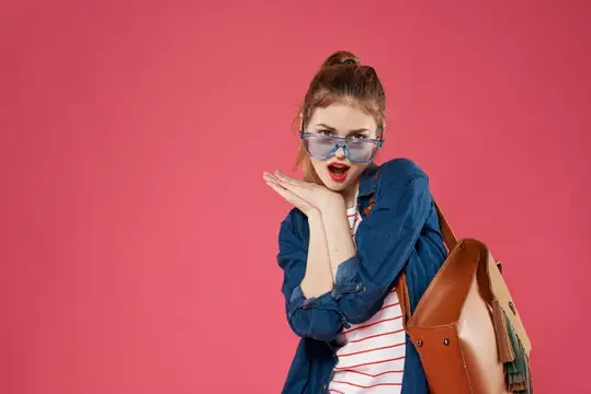 Эмоциональная женщина в очках, модной одежде и с рюкзаком, ведущая весёлый студенческий образ жизни