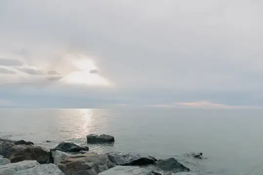 Спокойное море с каменистым берегом под пасмурным небом