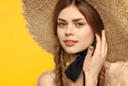 Молодая женщина в соломенной шляпе на жёлтом фоне