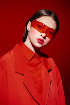 Азиатская девушка в красных очках и костюме на красном фоне