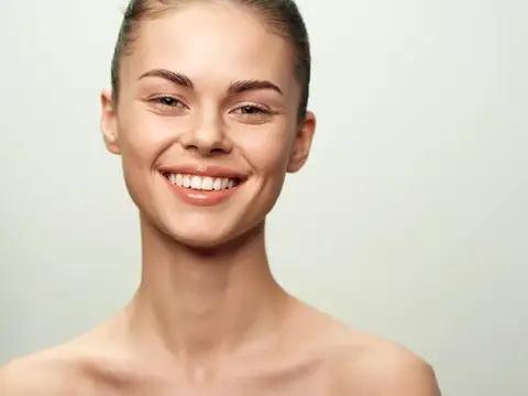 Улыбающаяся молодая женщина с гладкой кожей на светлом фоне