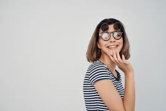 Улыбчивая девушка в тельняшке и круглых очках на сером фоне