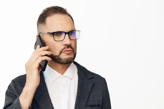 Серьёзный мужчина в очках и пиджаке говорит по телефону