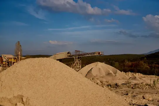 Песчаные насыпи и конвейер на карьере под вечерним небом