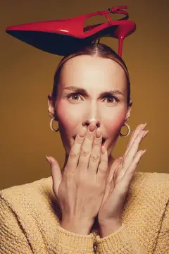 Удивлённая женщина с красной туфлей на голове