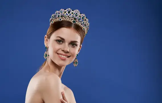 Очаровательная принцесса с диадемой на голове, в серьгах, с макияжем, позирует как модель