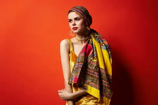 Рыжеволосая женщина в жёлтом платье с узорчатым платком на красном фоне
