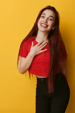 Смеющаяся девушка с длинными волосами на жёлтом фоне