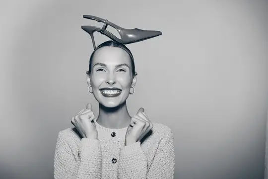 Улыбающаяся женщина с туфлей на голове в студии