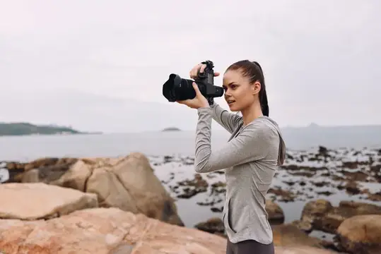 Юная модель занимается фотографией на побережье, запечатлевая безмятежные пейзажи