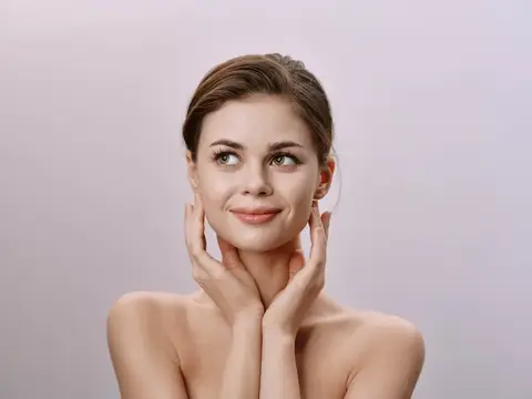 Молодая женщина с ухоженной кожей мягко касается лица руками