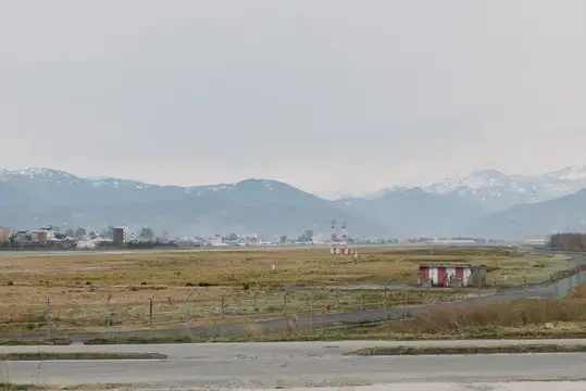 Пустынное поле аэродрома с забором и горами в дымке на горизонте