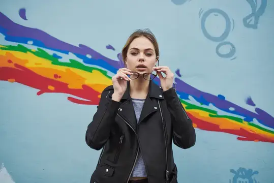 Женщины стоят рядом с граффити на стене в виде радуги на улице