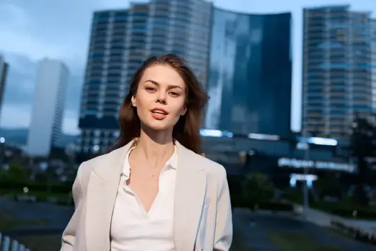 Молодая женщина в светлом пиджаке на фоне городских небоскрёбов
