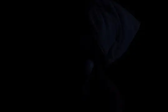 Силуэт человека в тёмном капюшоне на чёрном фоне
