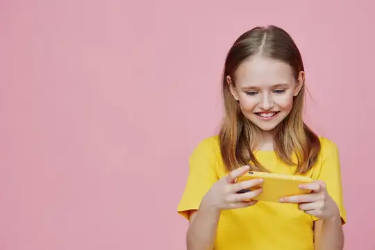 Улыбающаяся девочка со смартфоном на розовом фоне