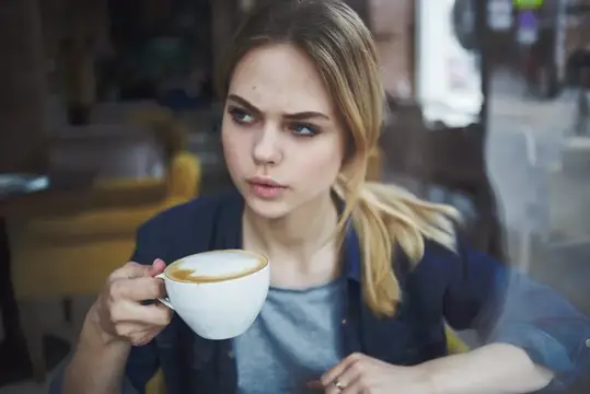 Задумчивая блондинка с чашкой кофе в кафе