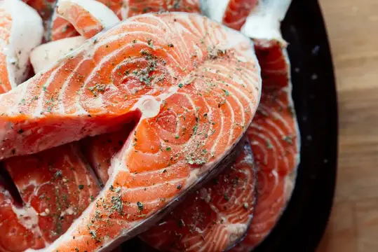 Свежие стейки лосося с травами на тёмном блюде