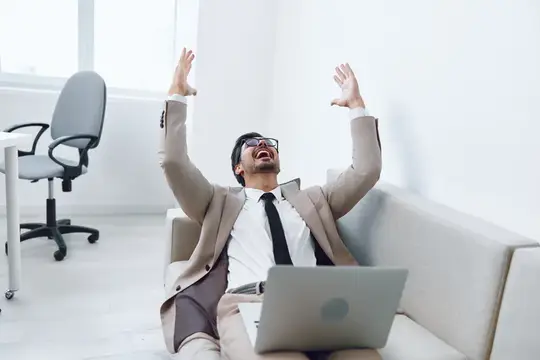 Успешный мужчина работает за ноутбуком в гостиной на диване