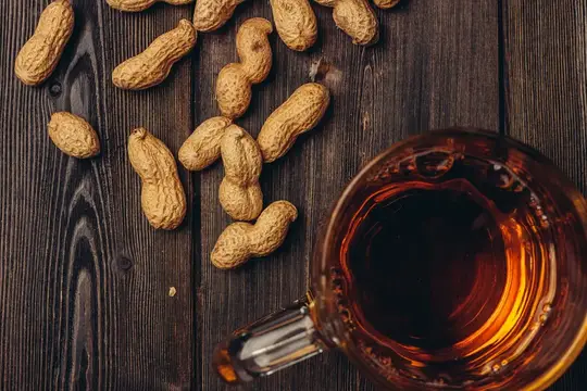 Земляные орехи и кружка чая на тёмном деревянном столе